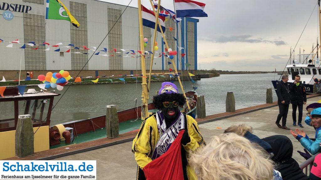 Intocht Sinterklaas Saint Nicolas im Buitenhaven Makkum 18 zwarte Piet mit gelben Umhang Sinterklaas im Buitenhaven Makkum - Schakelvilla Ferienhaus mit Sauna und Ruderboot in Makkum am IJsselmeer
