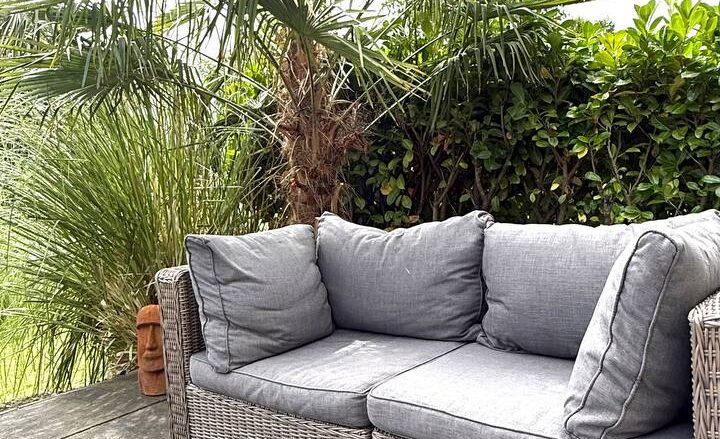 Gemütliche Lounge-Couch mit Korbgeflecht-Rahmen im Garten der Schakelvilla in Makkum